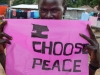 A young South Sudanese woman holds a sign stating 